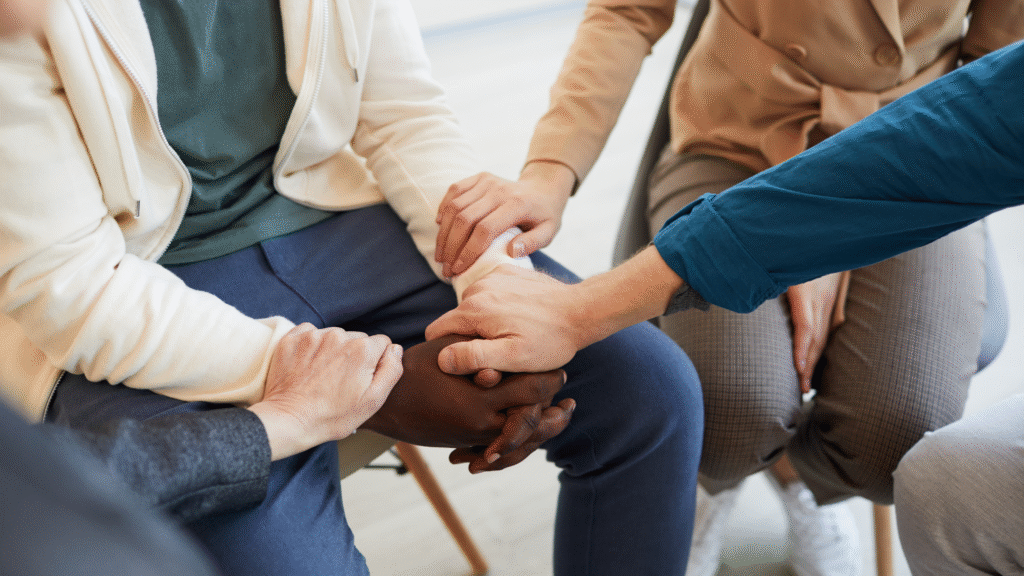 Close-up of supportive hands held together in a group, showing emotional support and connection – dementia care for older people in Christchurch and Tauranga
