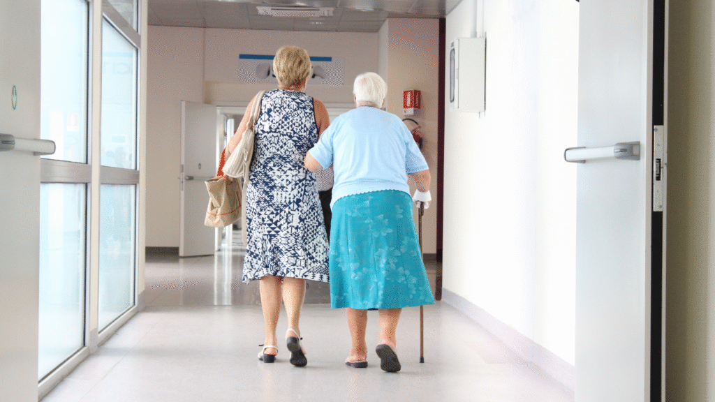 Older woman walking with family support down a hospital corridor after discharge – hospital to home care in Christchurch and Tauranga