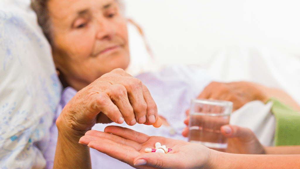 Older woman being assisted with medication and a glass of water after hospital discharge – home recovery support in Christchurch and Tauranga