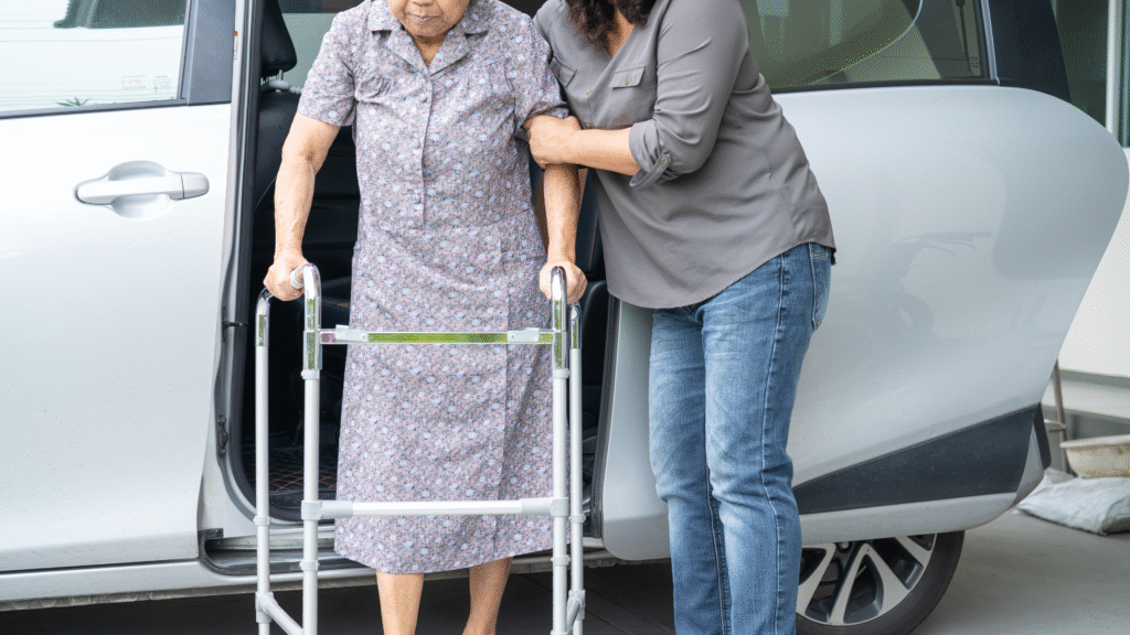 A family caregiver helping an older woman with a walker safely exit a car after hospital discharge in Christchurch and Tauranga