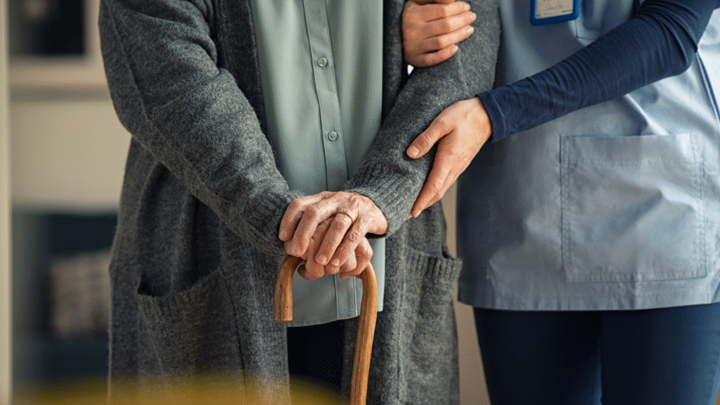 A caregiver gently supporting an older person with a walking aid at home after hospital discharge in Christchurch and Tauranga